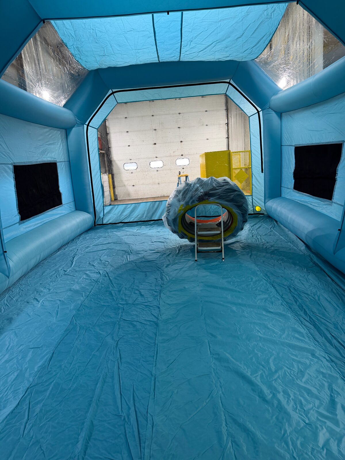 Inflatable spray booth interior with tractor rim masked and metal ready for color