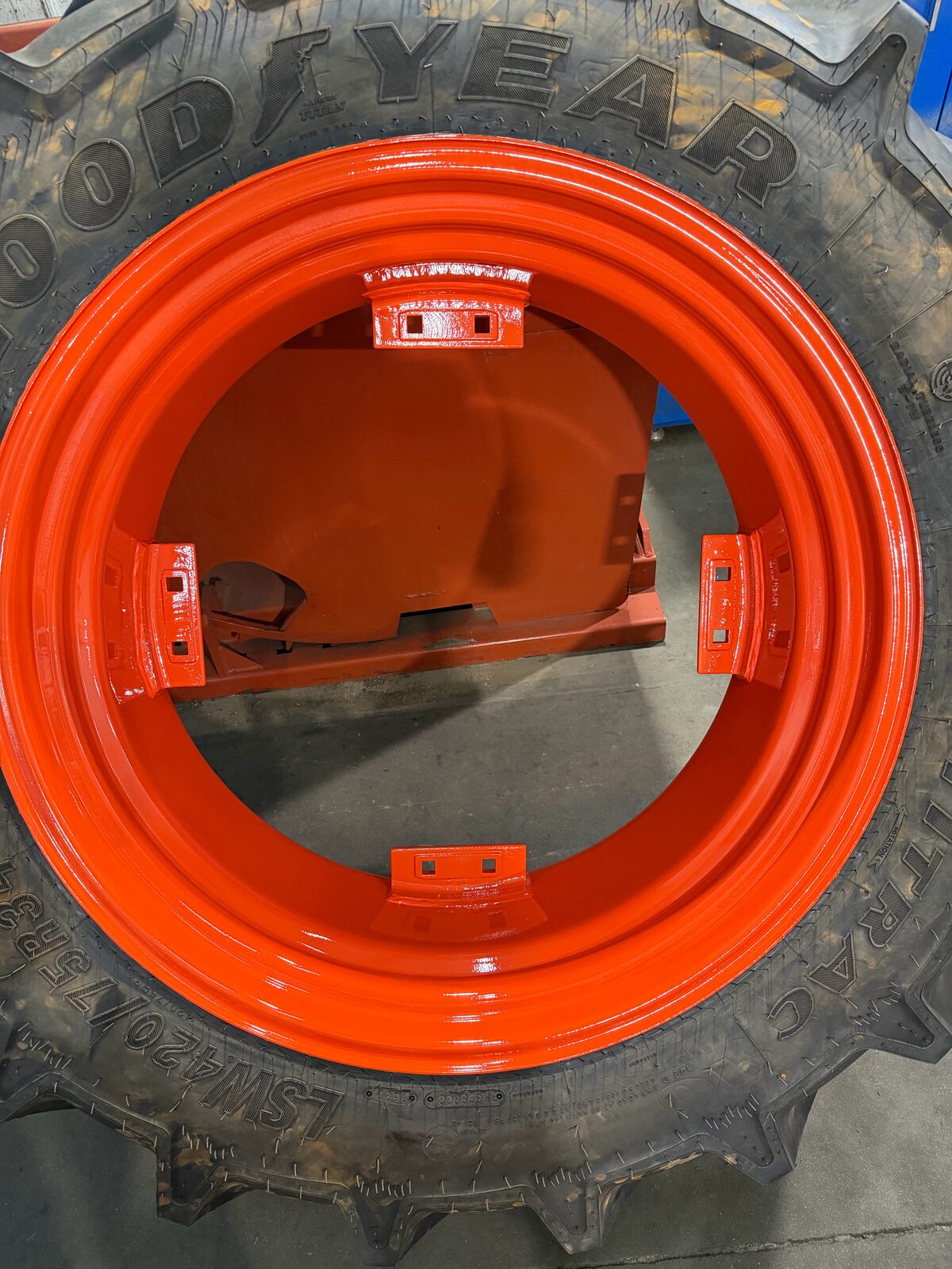 Tractor rim after booth paint in a glossy Kubota orange finish